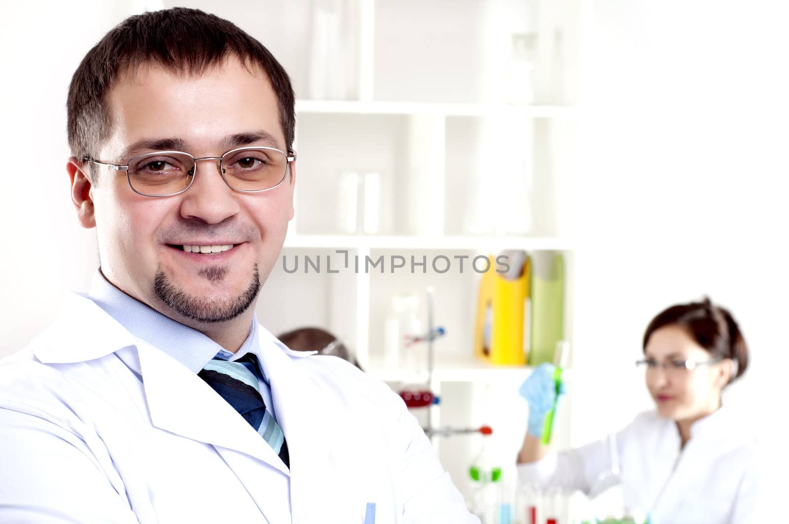 Three doctors are smiling at the camera in a doctors' office. Horizontally framed shot.