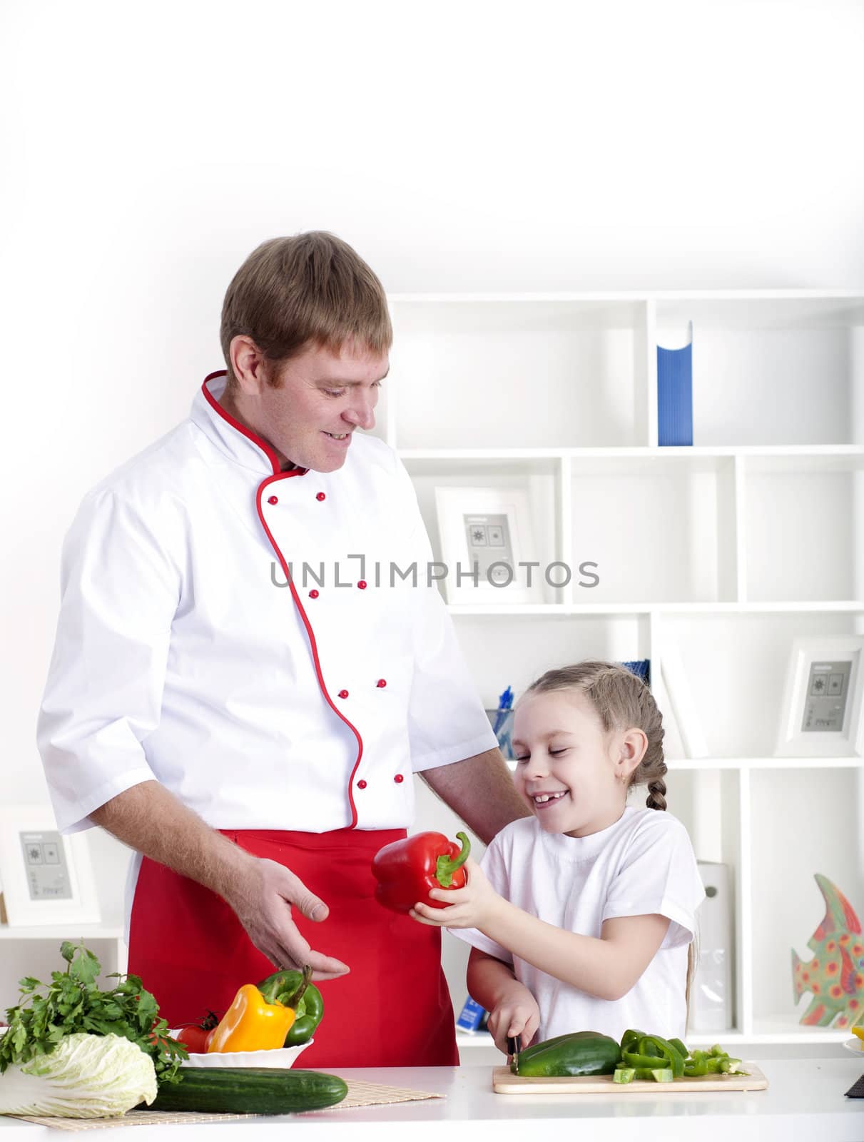 portrait of father and daughter cooking salad together in the kitchen