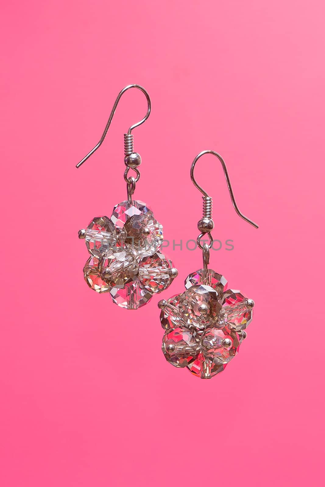 Shining elegant modern earrings with zircons on pink background