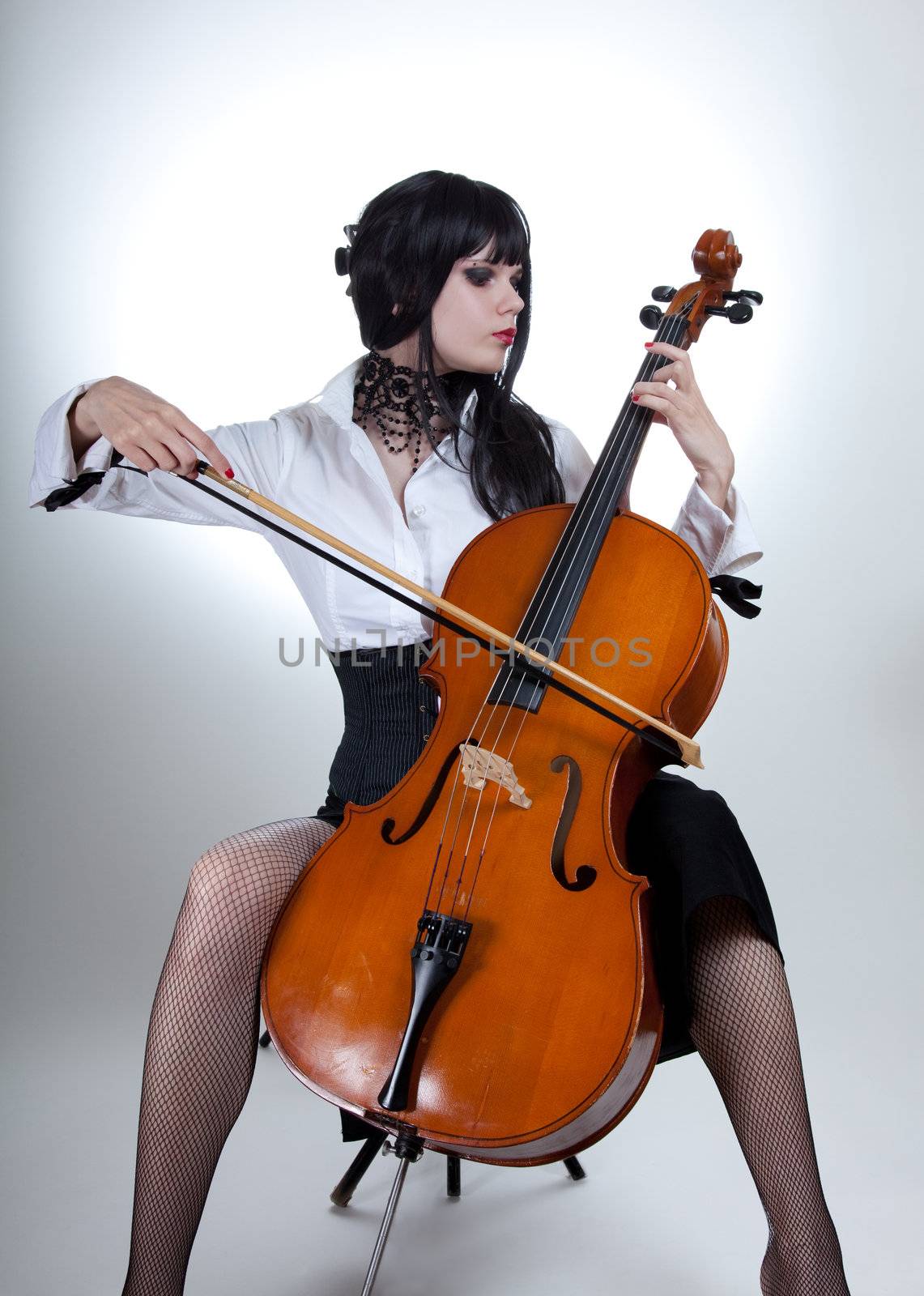 Romantic girl playing cello, studio shot over white background 