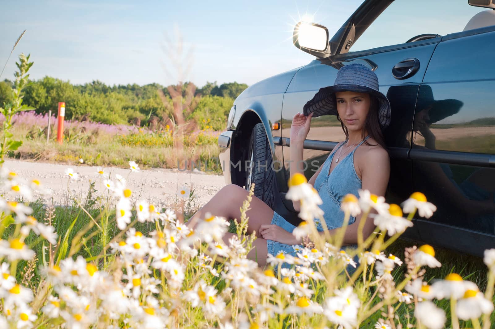 Beautiful brunette woman sitting near car by anytka