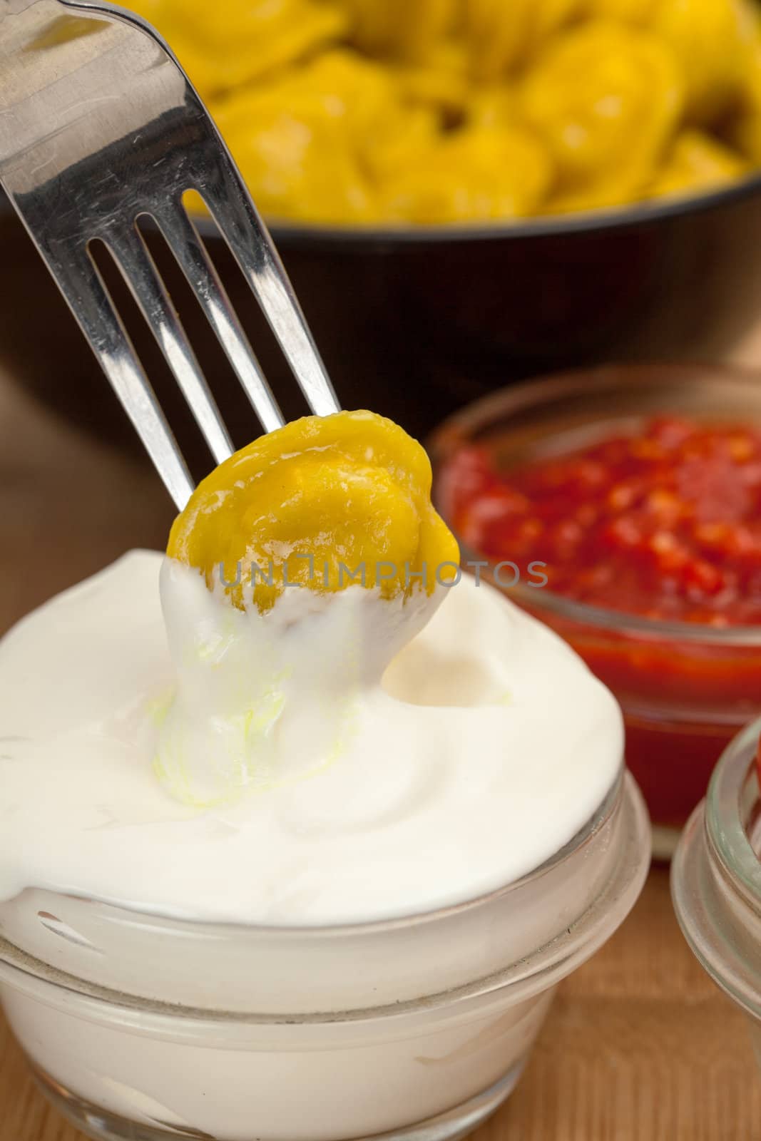 Yellow dumplings with sour cream on a plate closeup