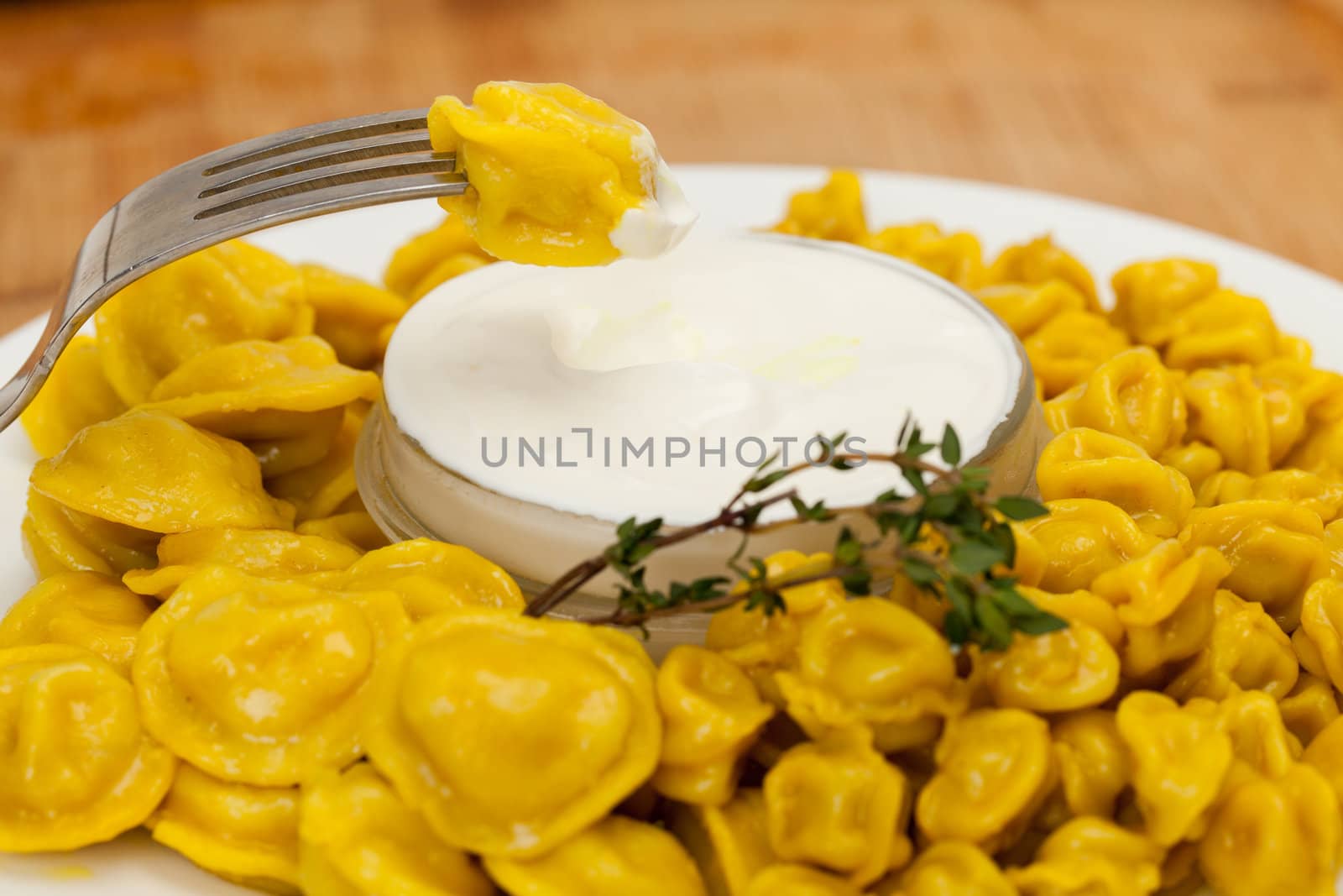 Yellow dumplings with sour cream on a plate closeup