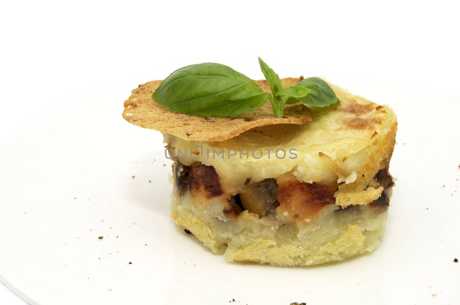 potato casserole decorated with greens and tomato on a white background