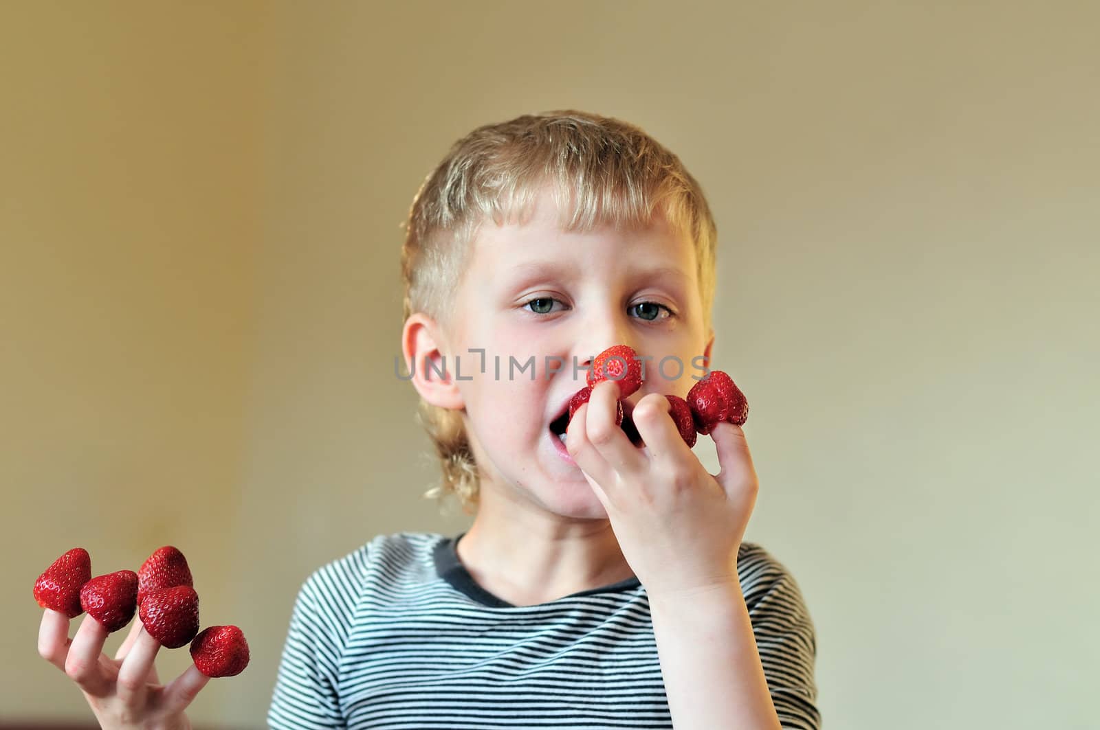 boy eating strawberry put on his fingers  