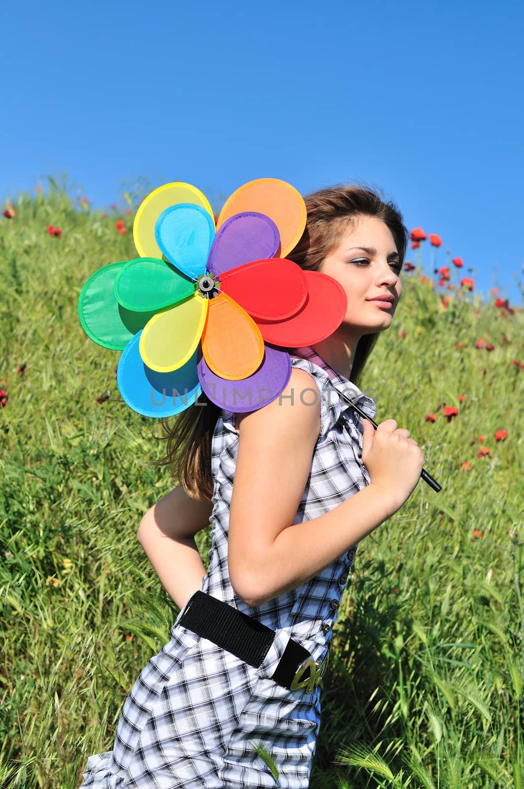 girl with windmill walking by the poppy field 