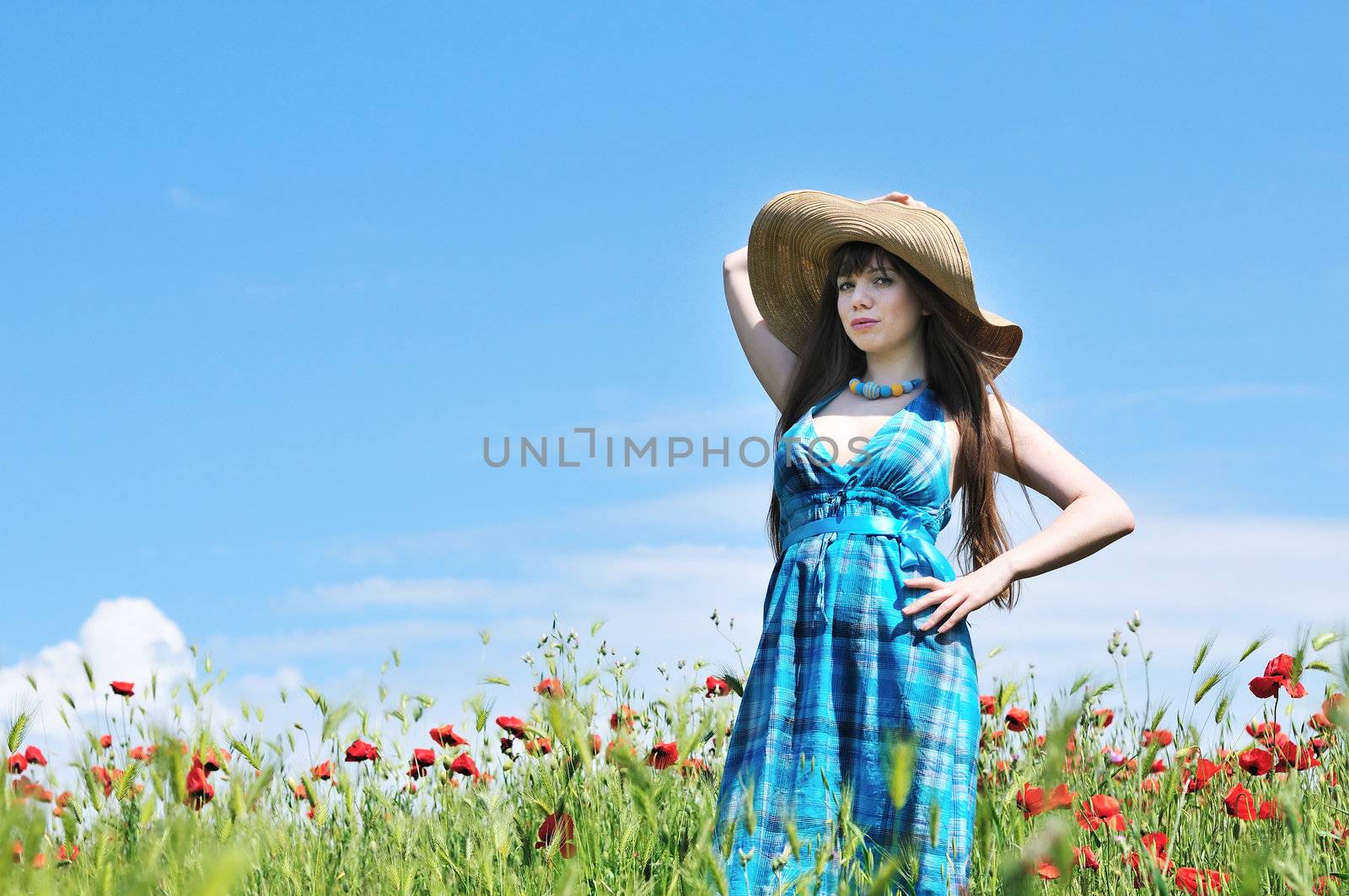 young woman wearing srtaw hat standing in the poppy field