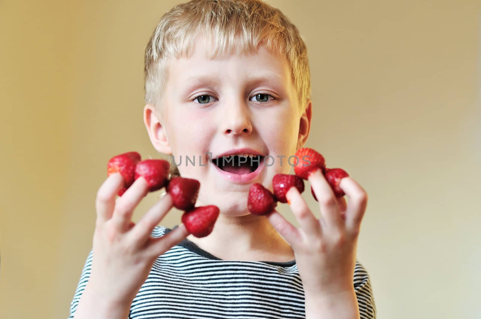 little boy enjoying sweet strawberry put on his fingers