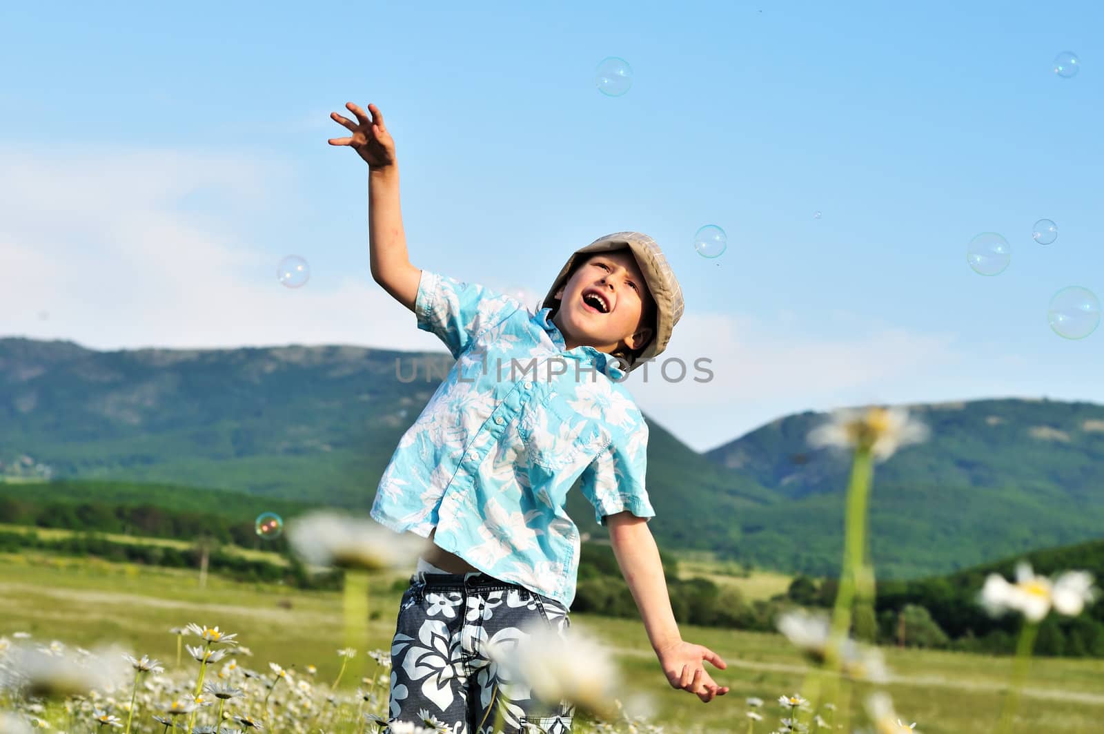 jumping little boy wants to catch soap bubbles