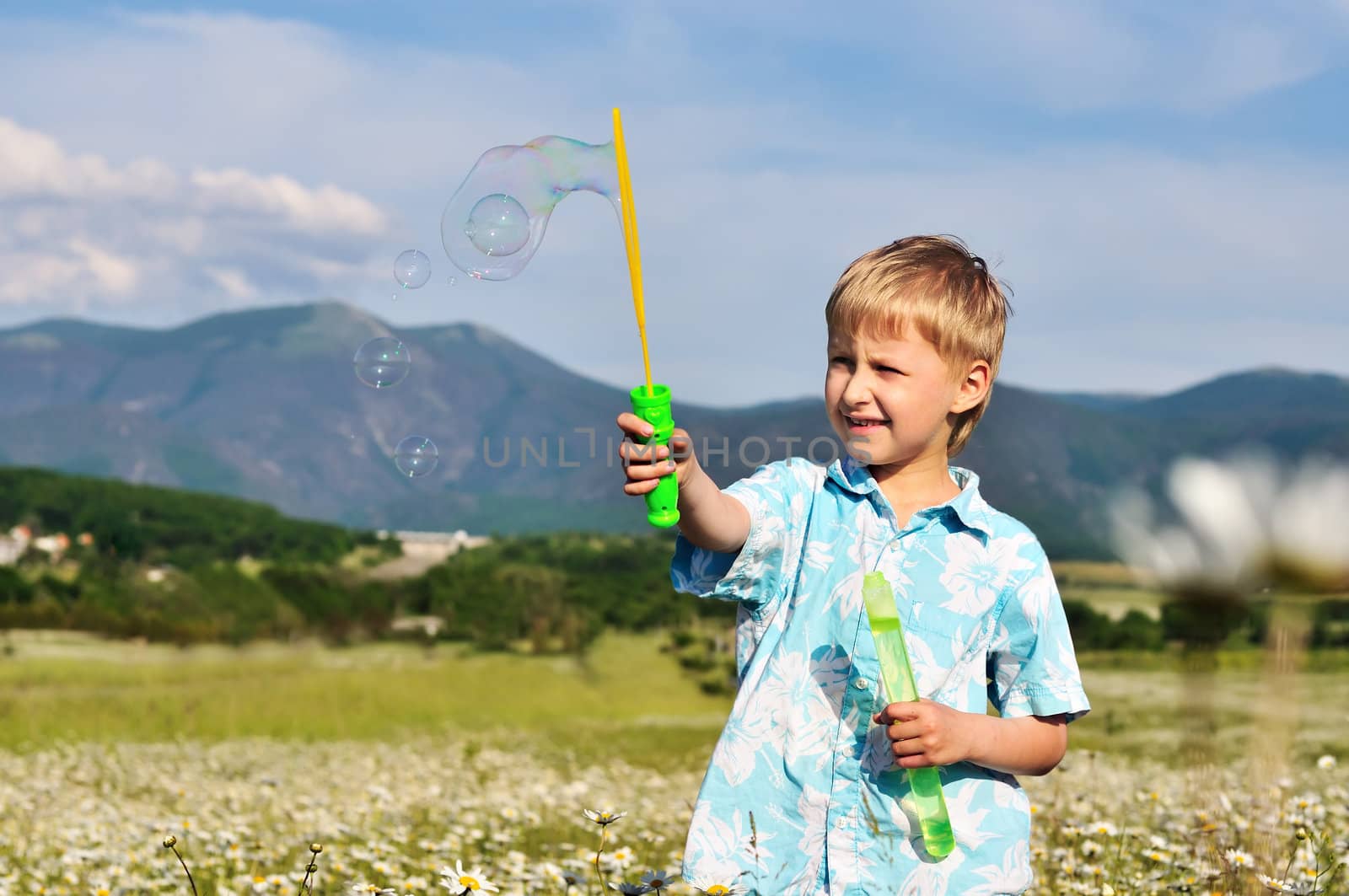 funny little boy blowing soap bubbles outdoors 