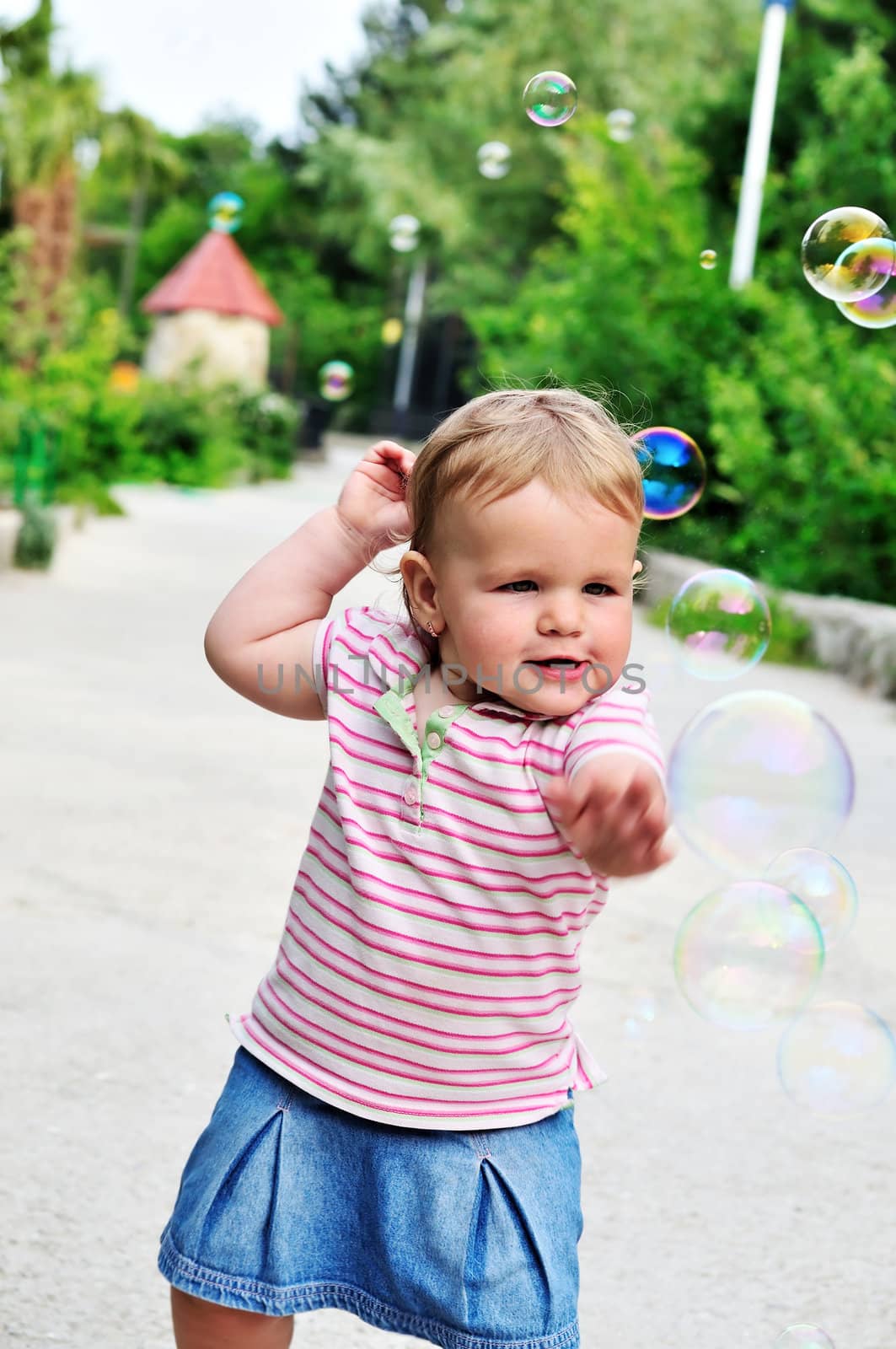 baby girl catching soap bubbles in the park