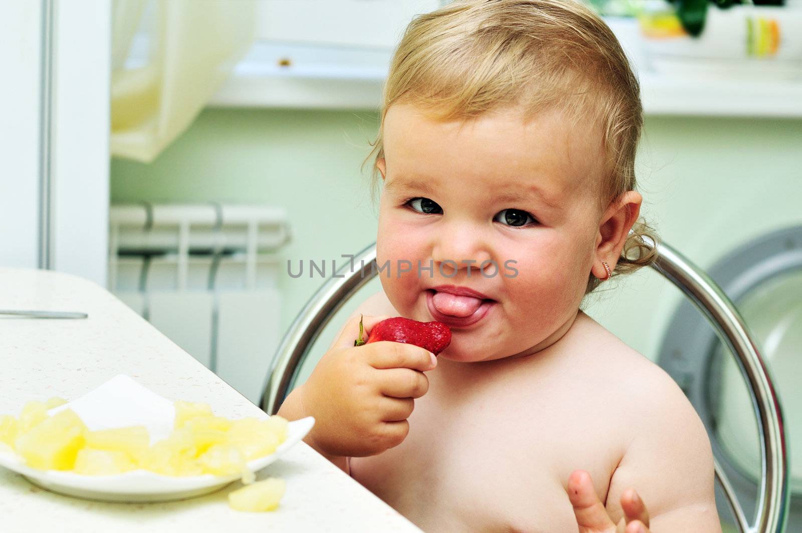 little funny baby girl tasting fresh strawberry