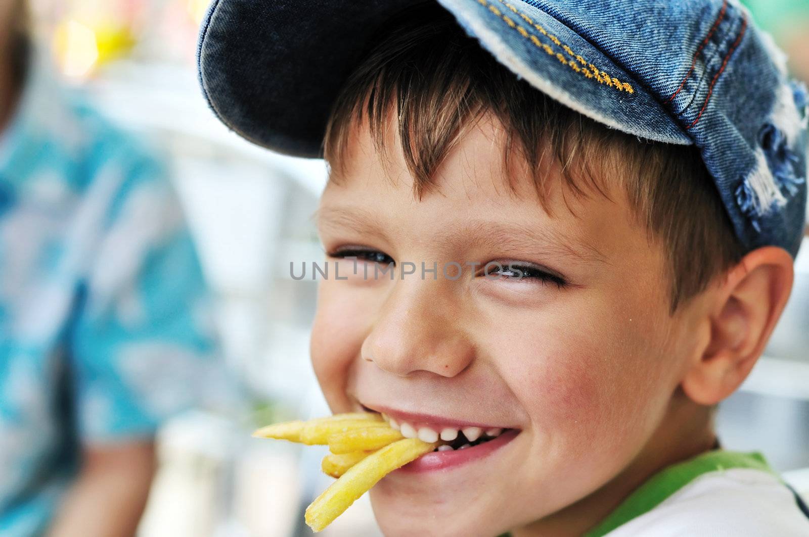 little boy eating french fries in cafe 