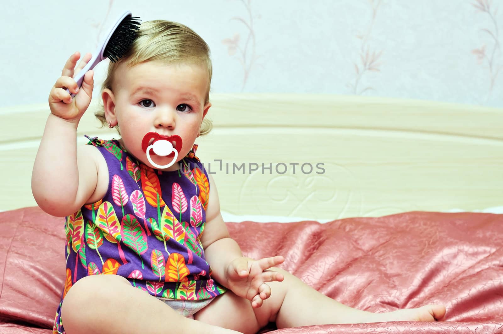 baby girl using comb at home on the bed