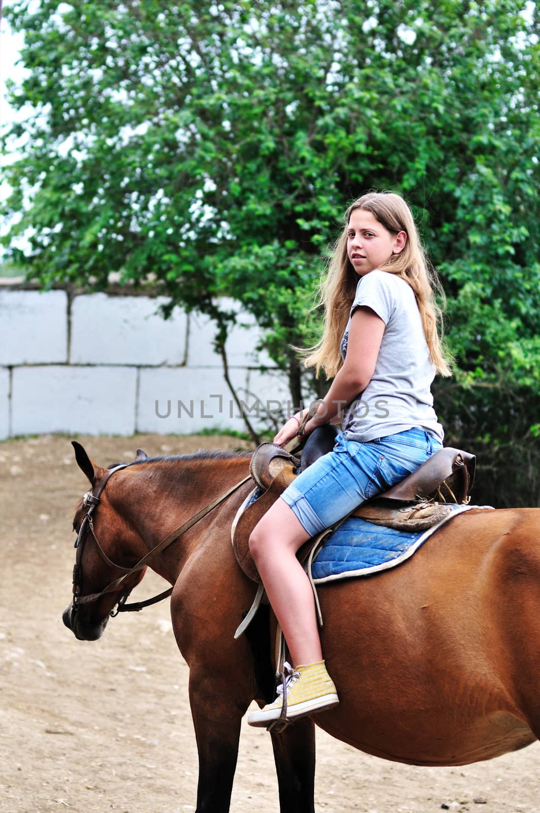 teen longhaired girl sitting on the horse 
