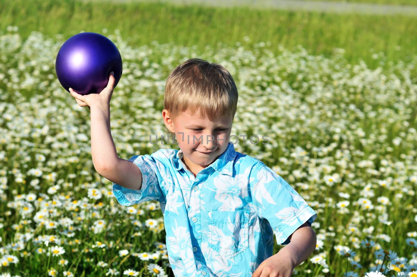 funny boy playing ball at the daisy field 