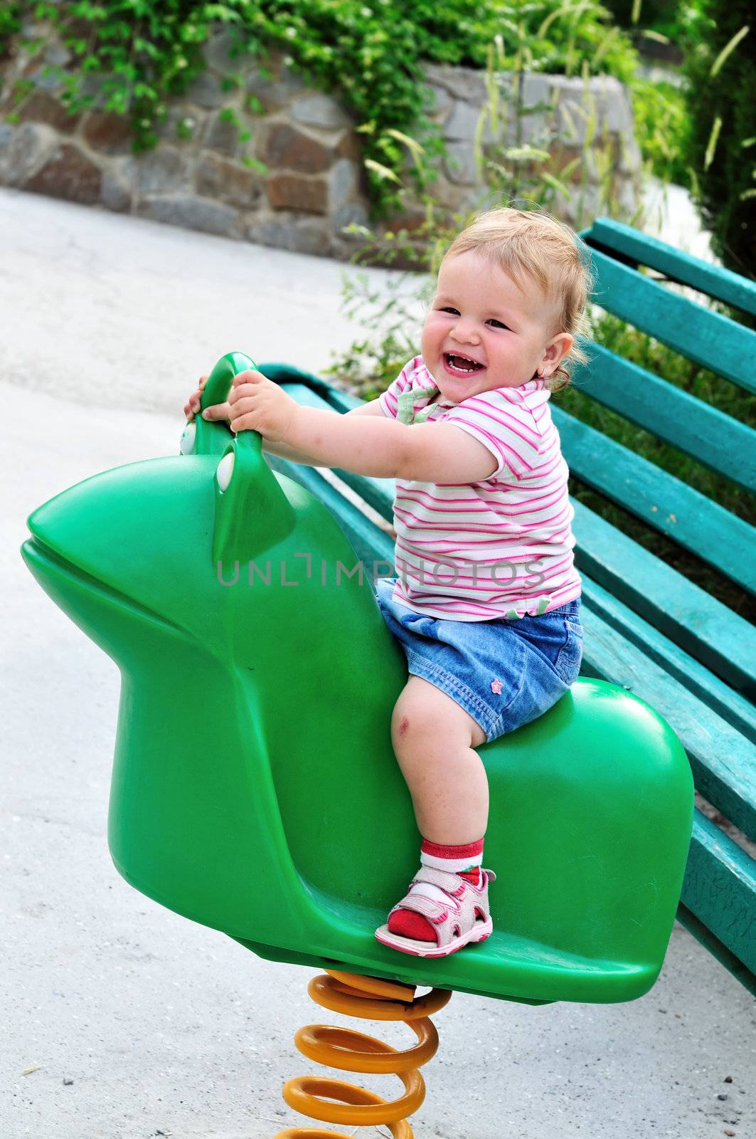 Small funny girl girl on spring frog swing