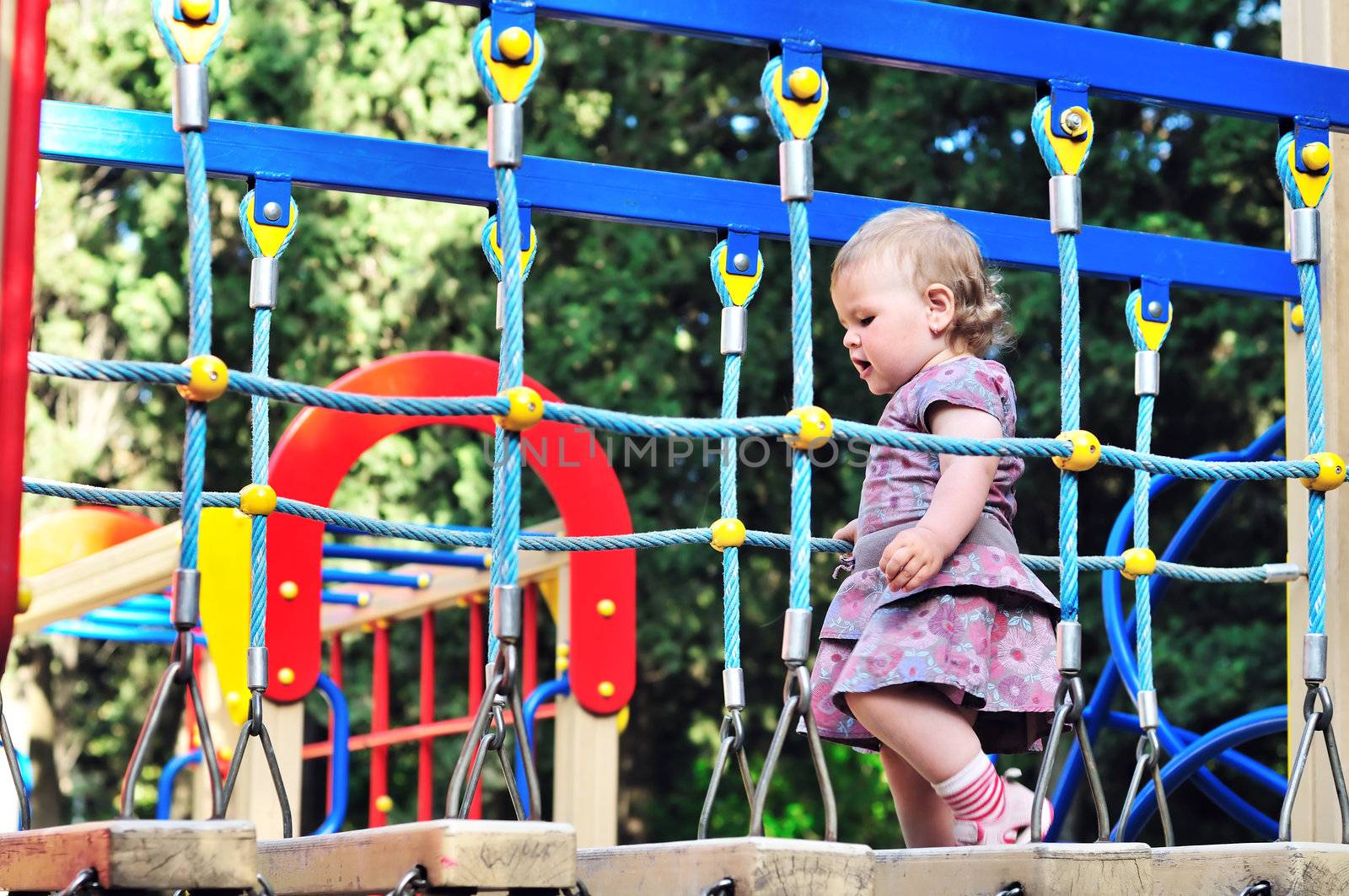 Little baby girl walking on playground in the park 