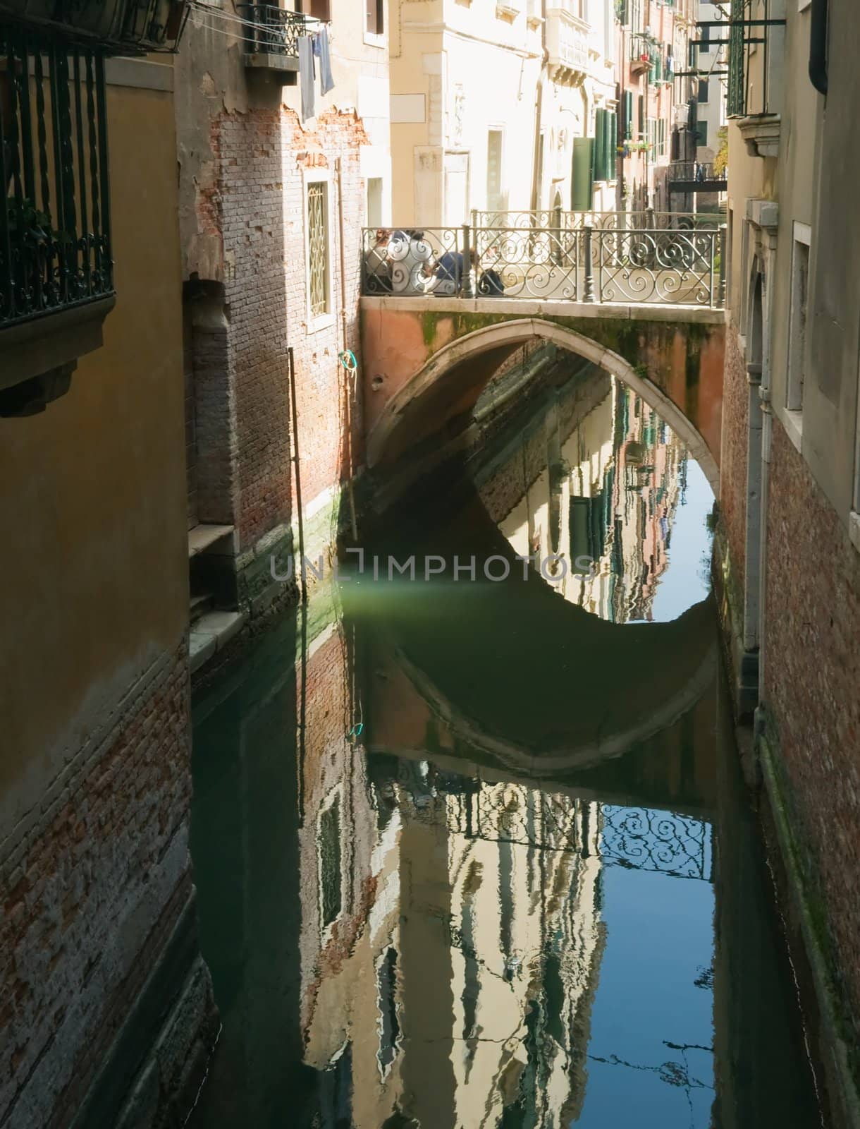 Venetian canal, a bridge, reflections in the water at the sunset