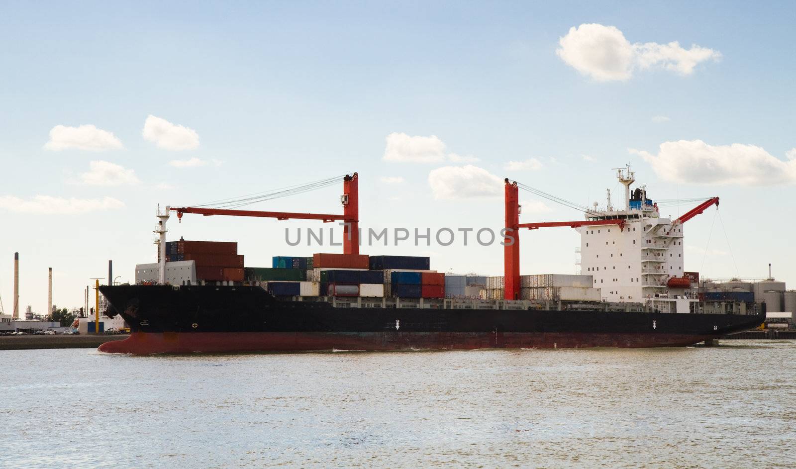 Big container ship with onboard cranes on the river coming in to port