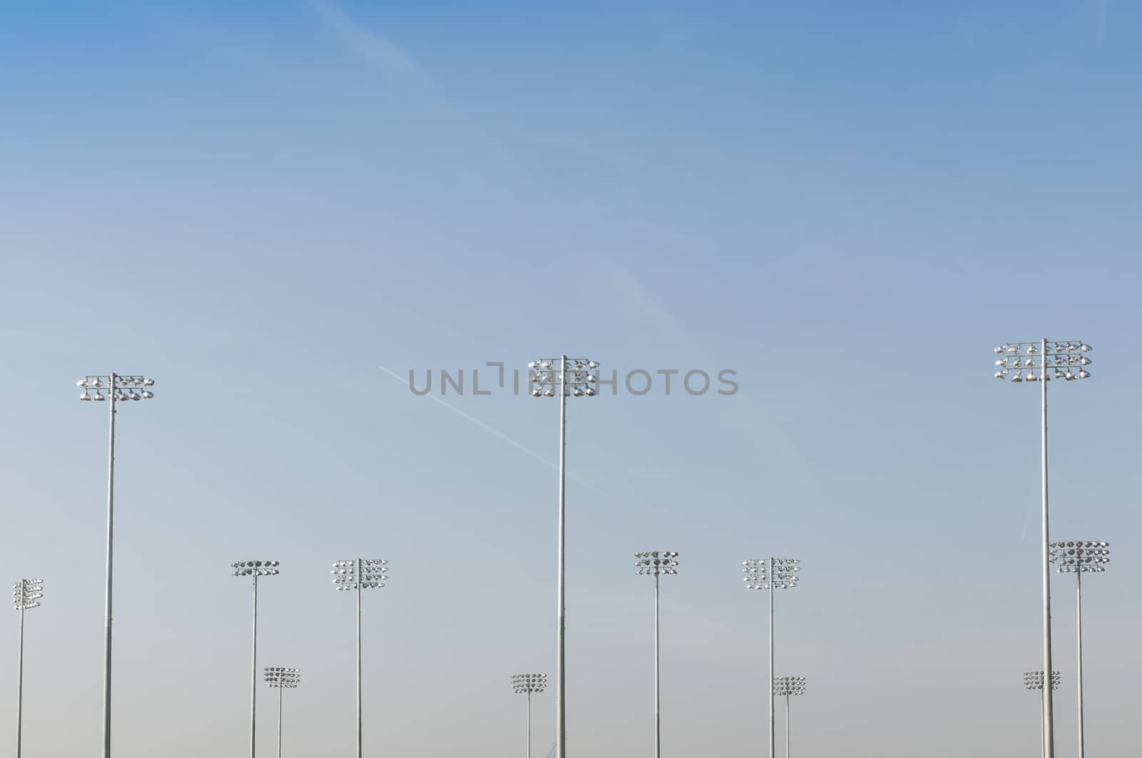 Cropped shot of illumination towers from behind, with blue sky and loads of copy space