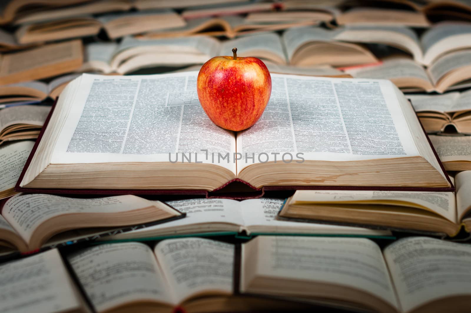 Red and delicious apple on big heap of books