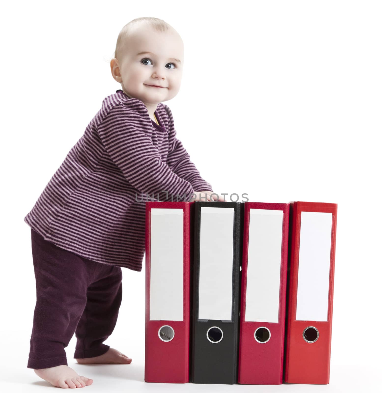 toddler standing next to four file folder in light background