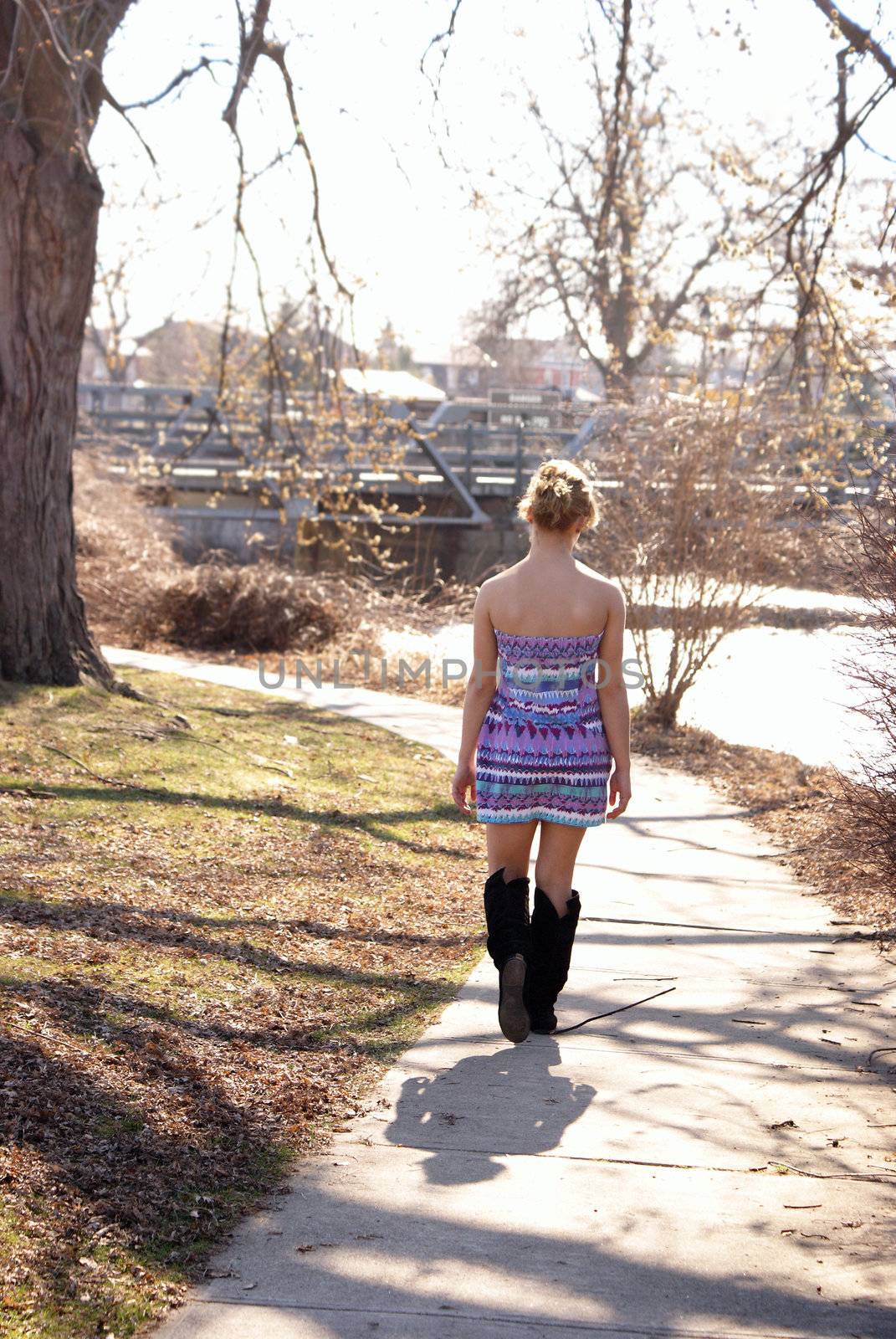 A young woman walks through the park near the river on this sunny spring day.