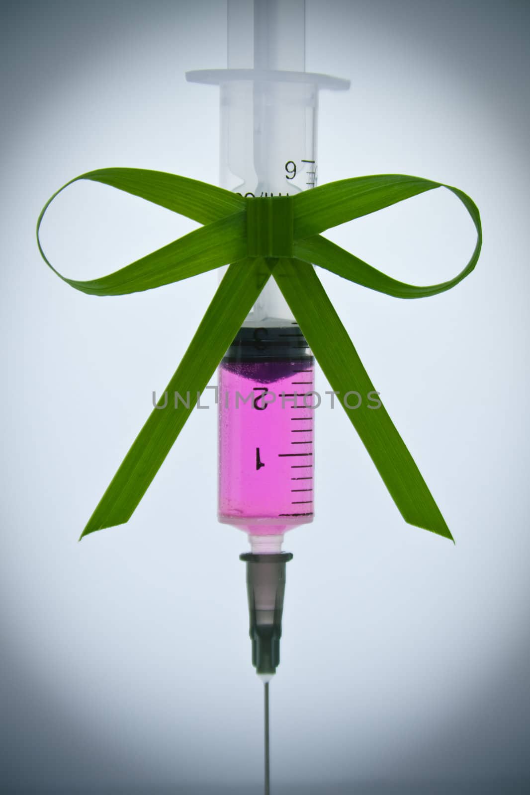 syringe with a pink liquid with a ribbon of grass with a vignette