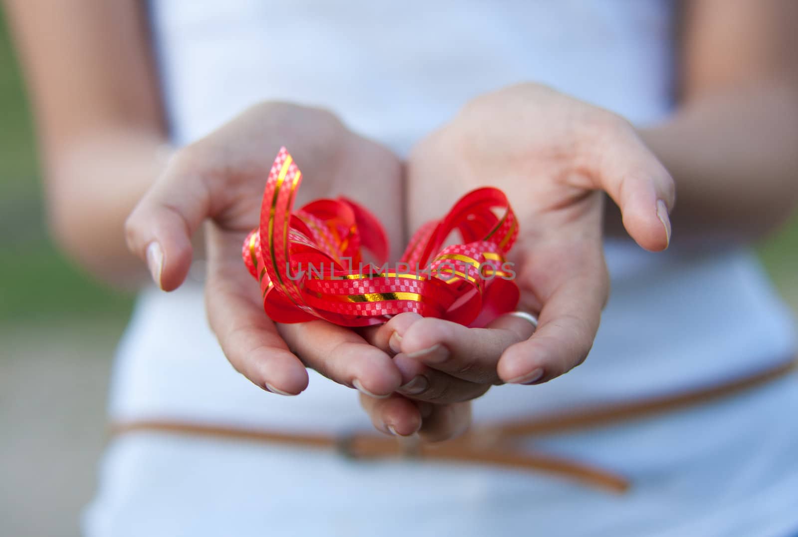 young woman holds a gift red bow in hands.