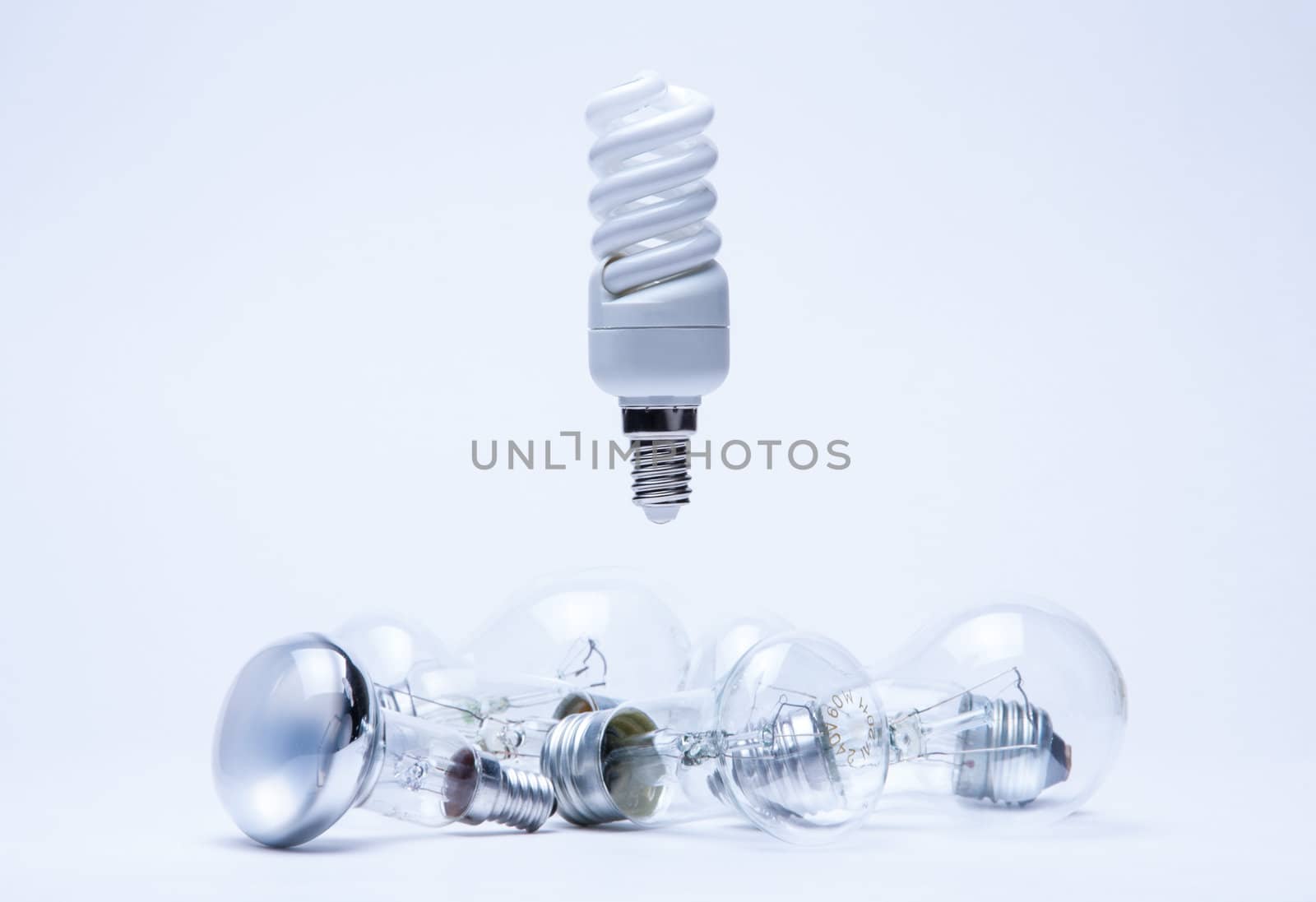 energy saving light hanging over incandescent lamps on white