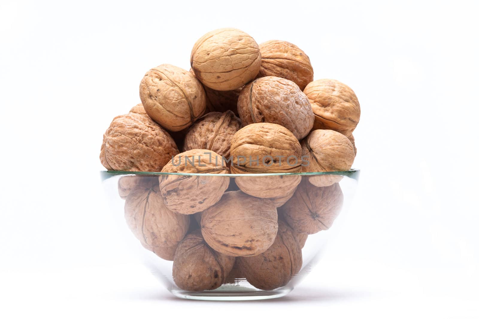 Walnuts are a lie in a glass bowl isolated on a white background