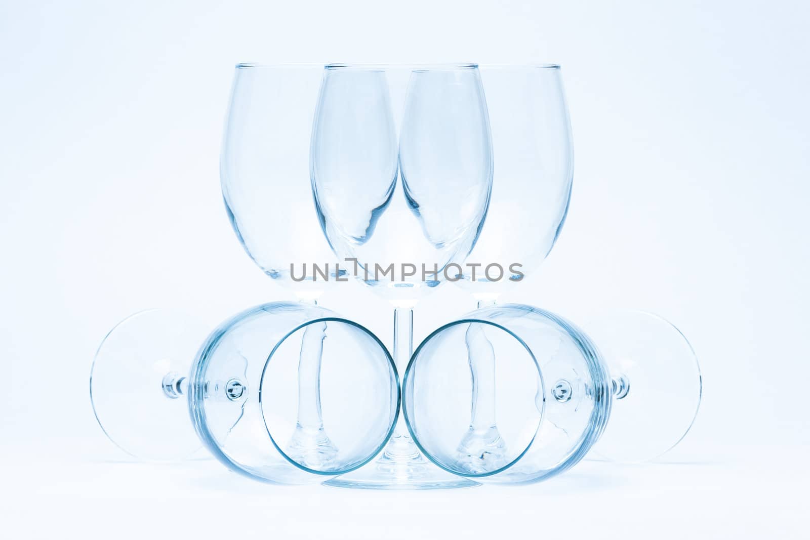 Empty wine glasses stand and lie symmetrically on a white background