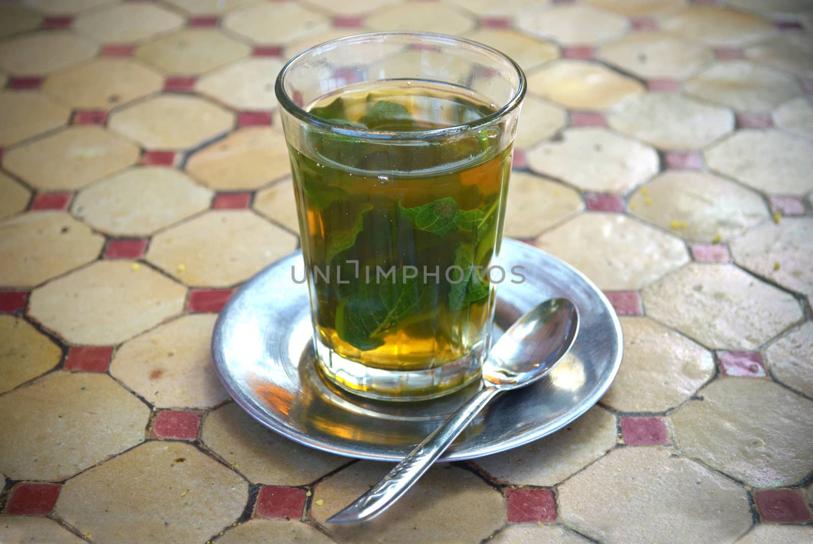 Glass of traditional mint tea and metal spoon and saucer