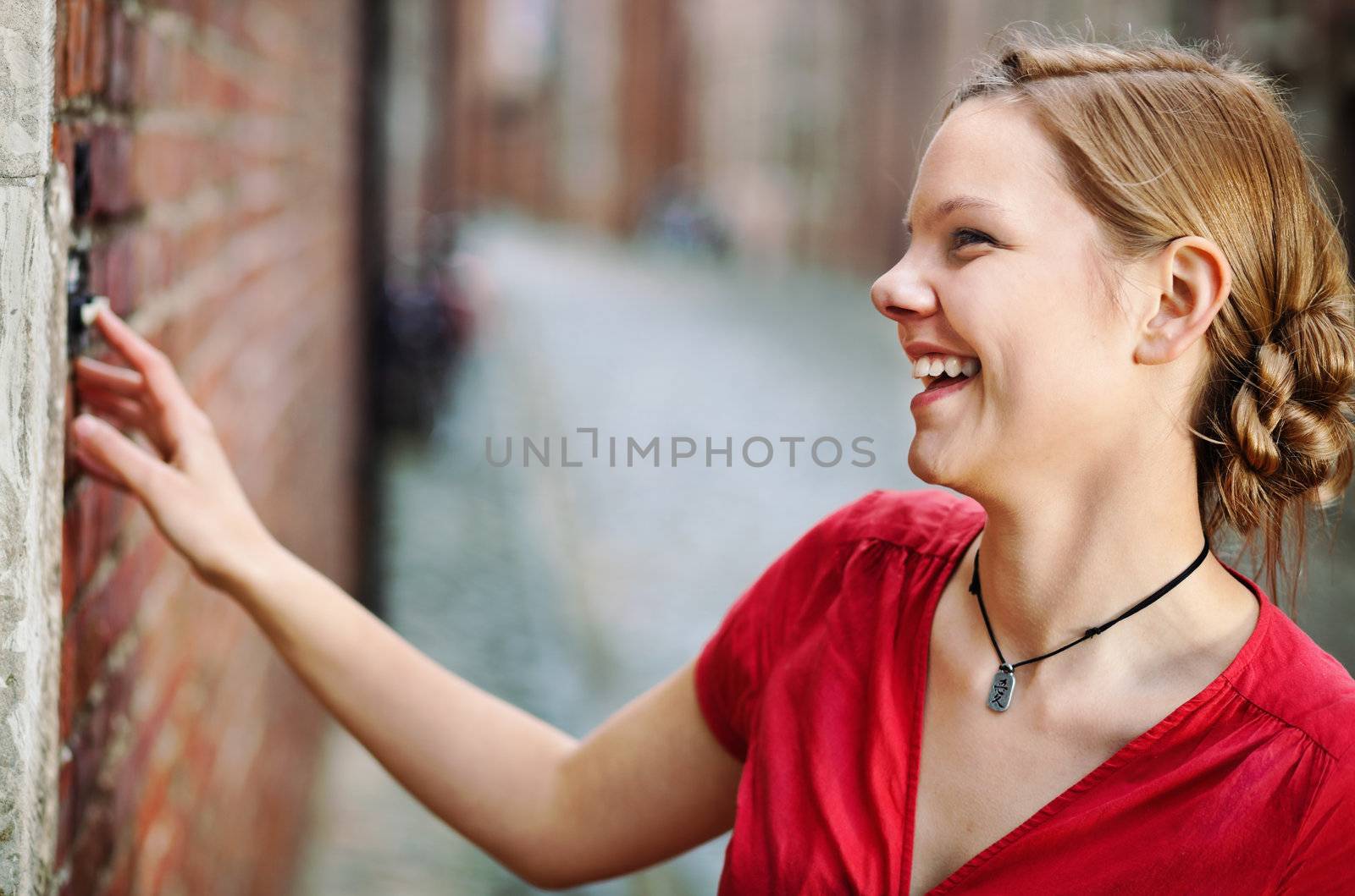 Pretty young smiling woman ringing at the door bell 