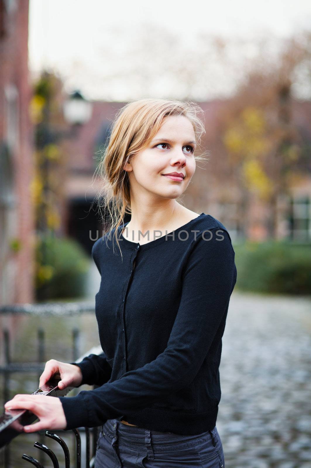 Portrait of a pretty young blond woman standing on a bridge in and turning back