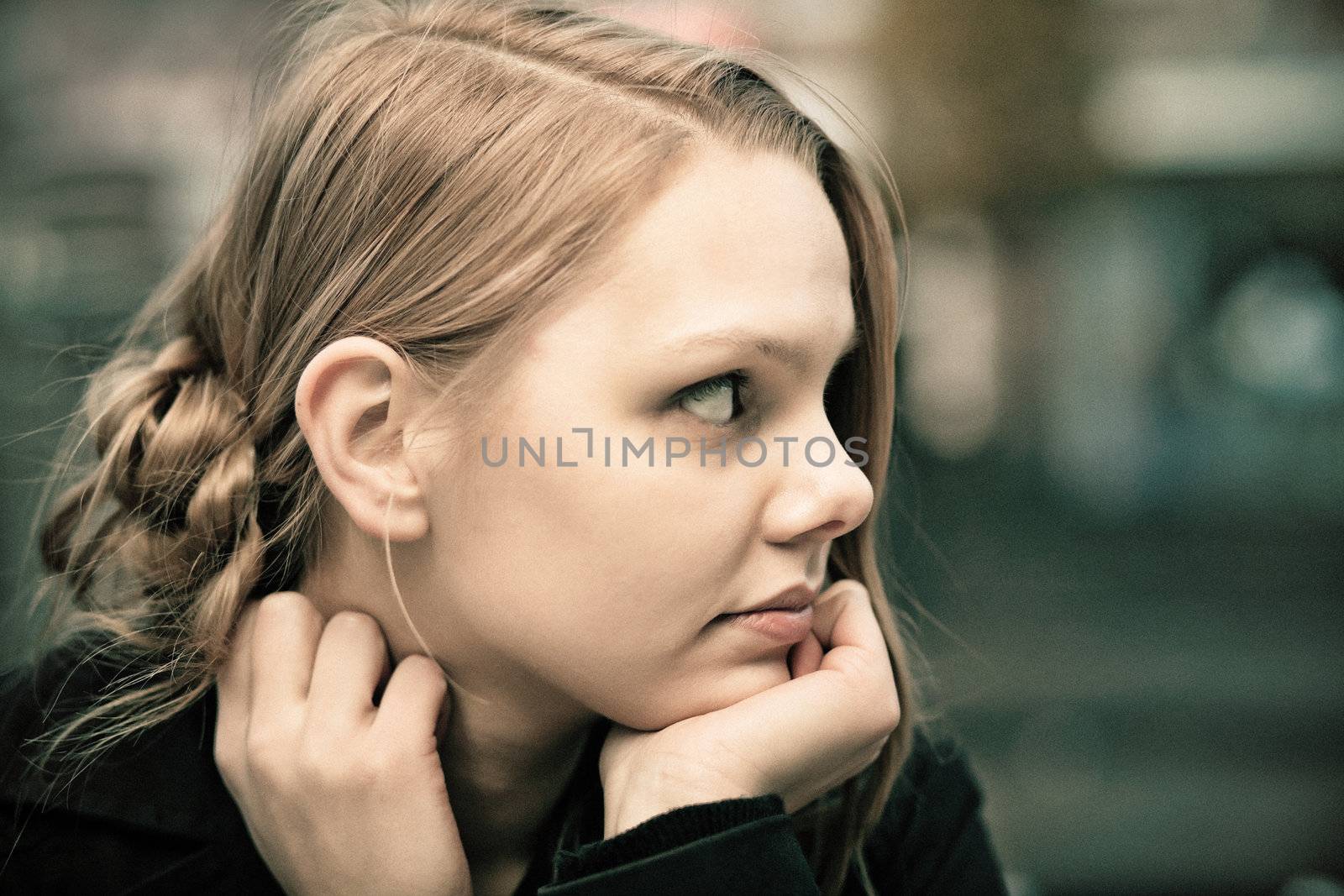 Profile of a pensive young blond woman, desaturated, film grain