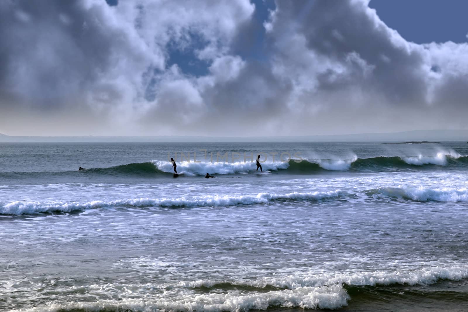 beautiful clean atlantic ocean with surfers catching the waves during a storm on Irelands coast