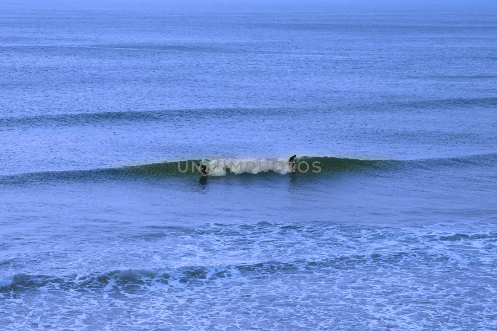beautiful clean atlantic ocean with two surfers catching the waves on Irelands coast