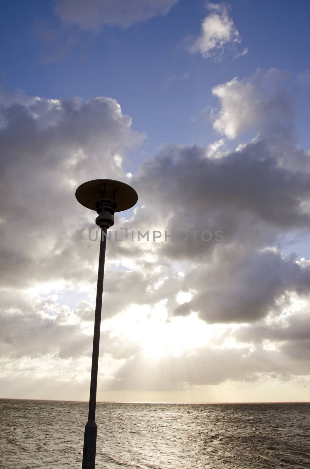 park lamp on background of cloudy sky and sunlight by sauletas
