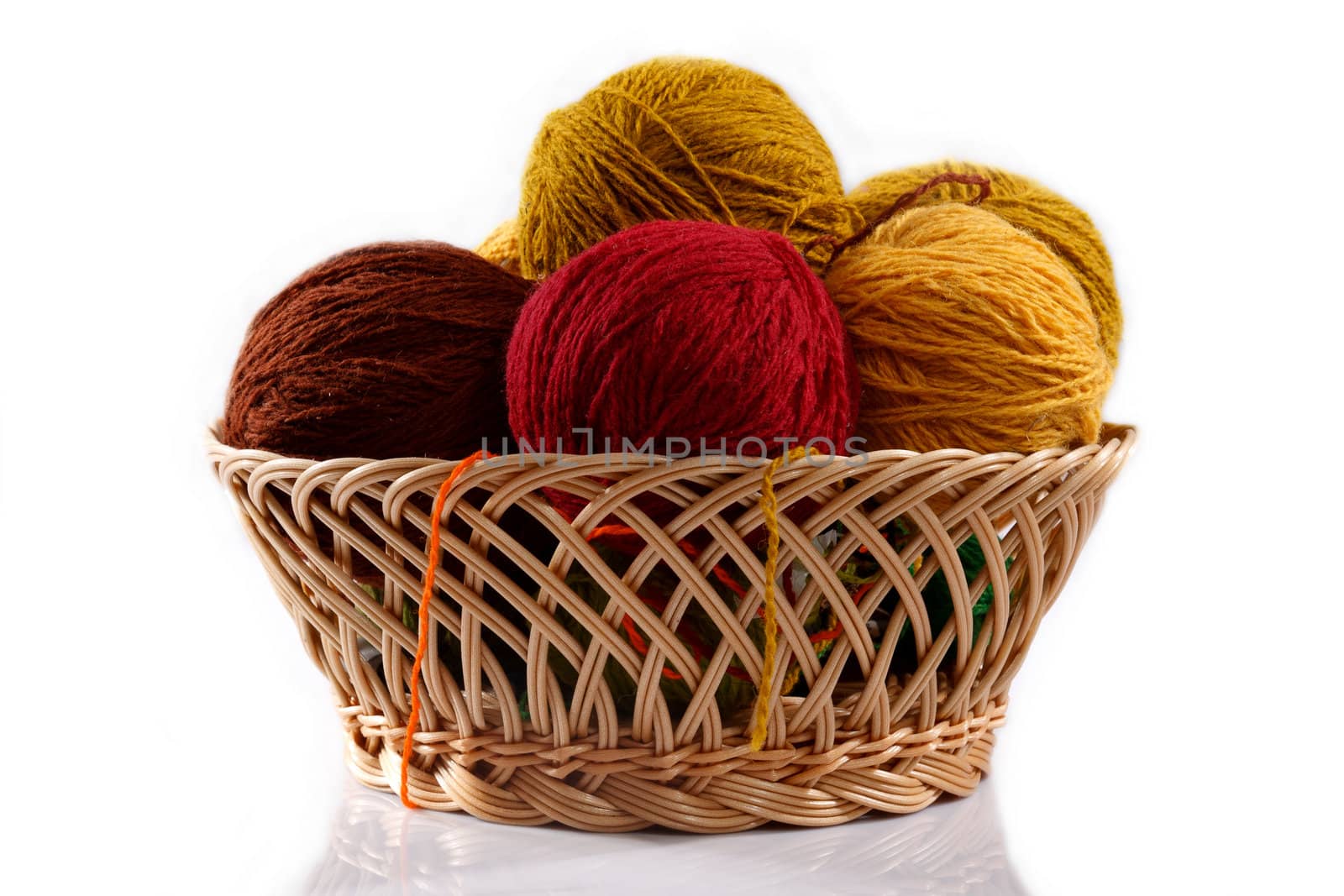wicker basket with colorful balls of wool on a white background 