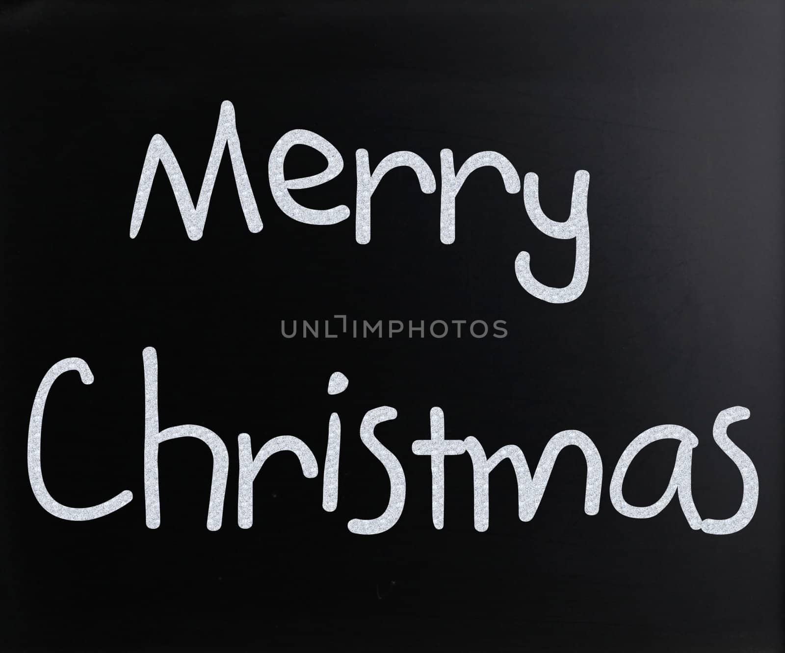 "Merry Christmas" handwritten with white chalk on a blackboard