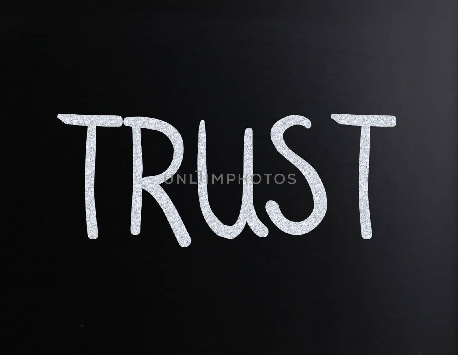 The word "Trust" handwritten with white chalk on a blackboard
