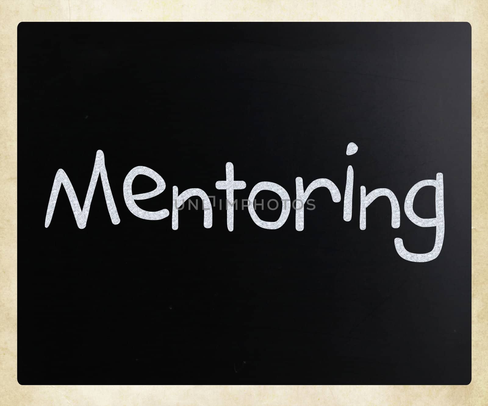 The word "Mentoring" handwritten with white chalk on a blackboar by nenov