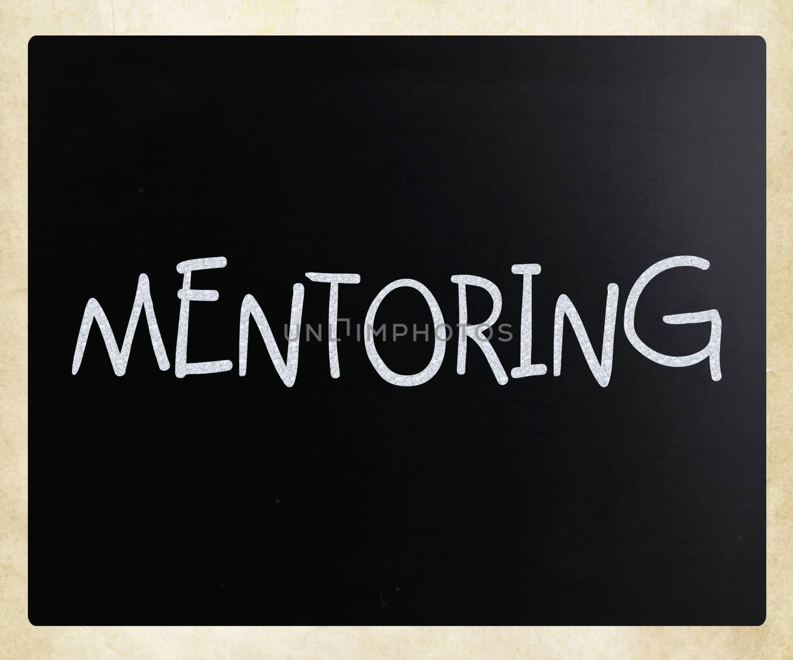 "Mentoring" handwritten with white chalk on a blackboard by nenov