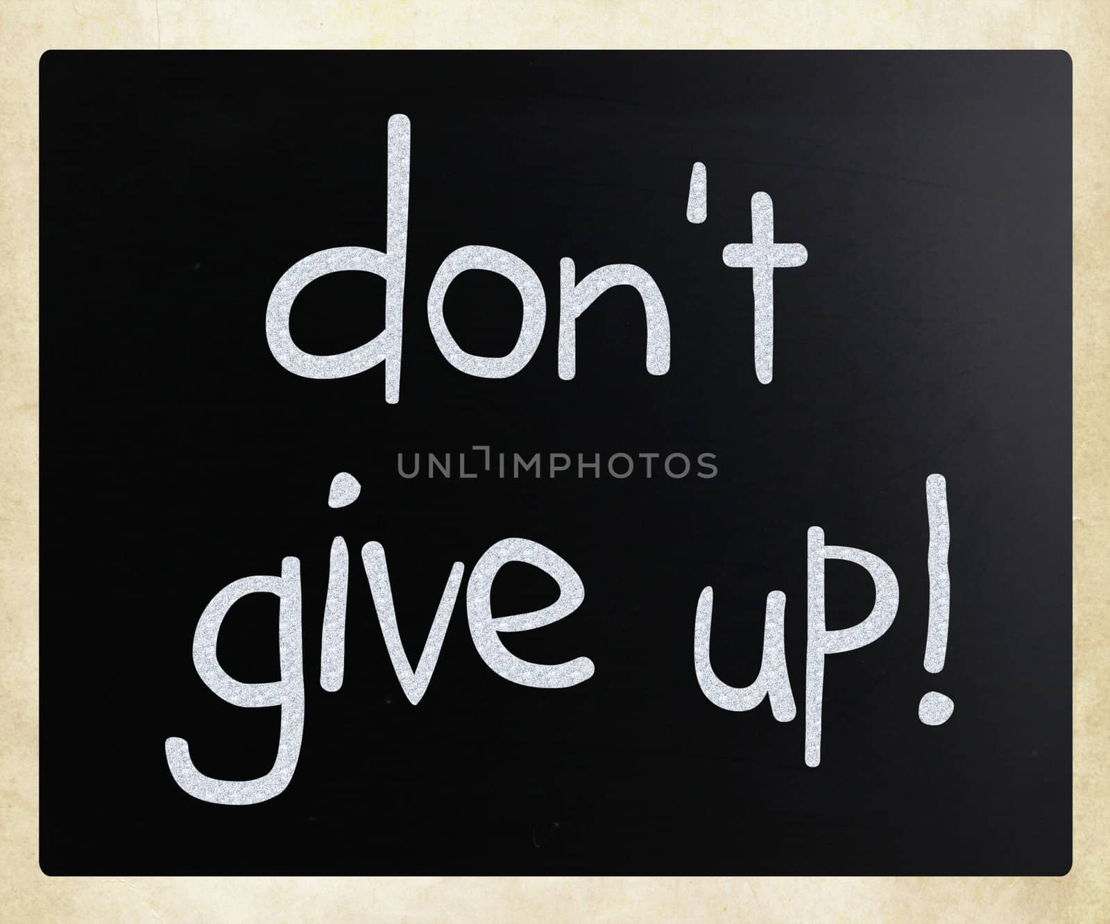 "Don't give up" handwritten with white chalk on a blackboard
