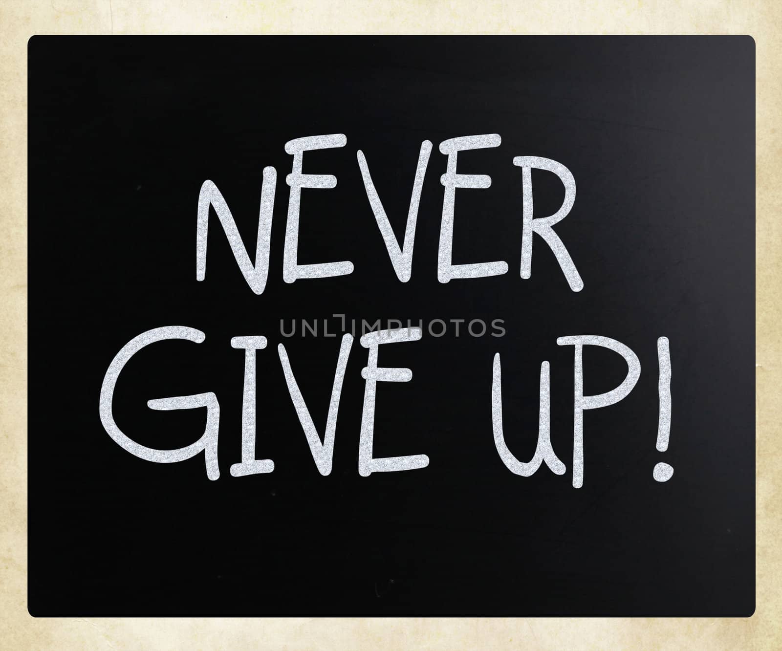 "Never give up" handwritten with white chalk on a blackboard