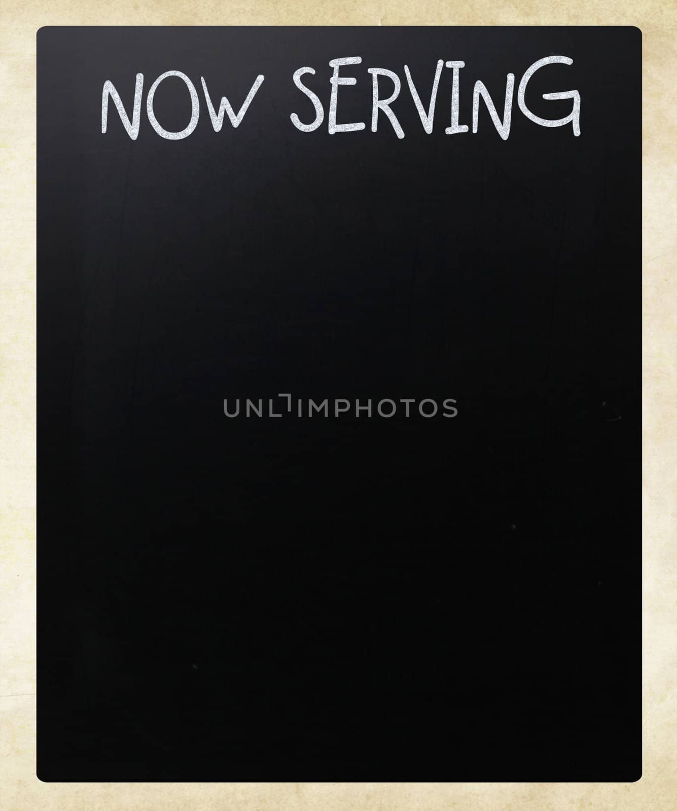"Now serving" handwritten with white chalk on a blackboard