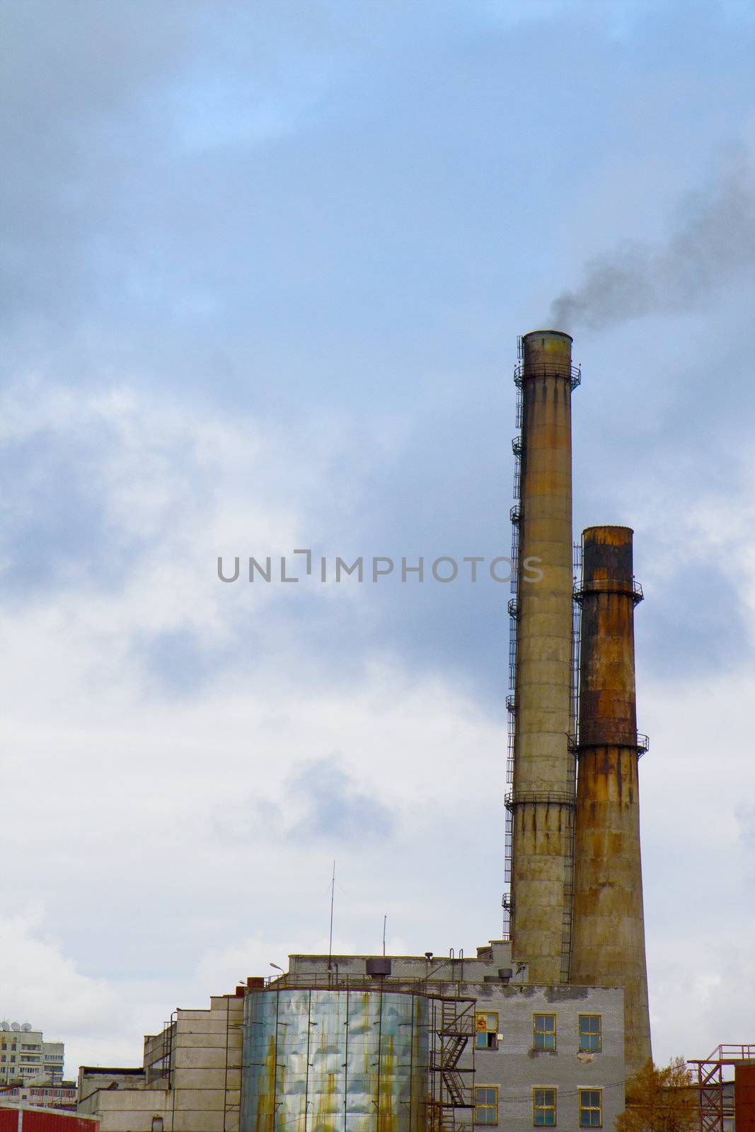 Two old factory smokestack tube against the cloudy sky