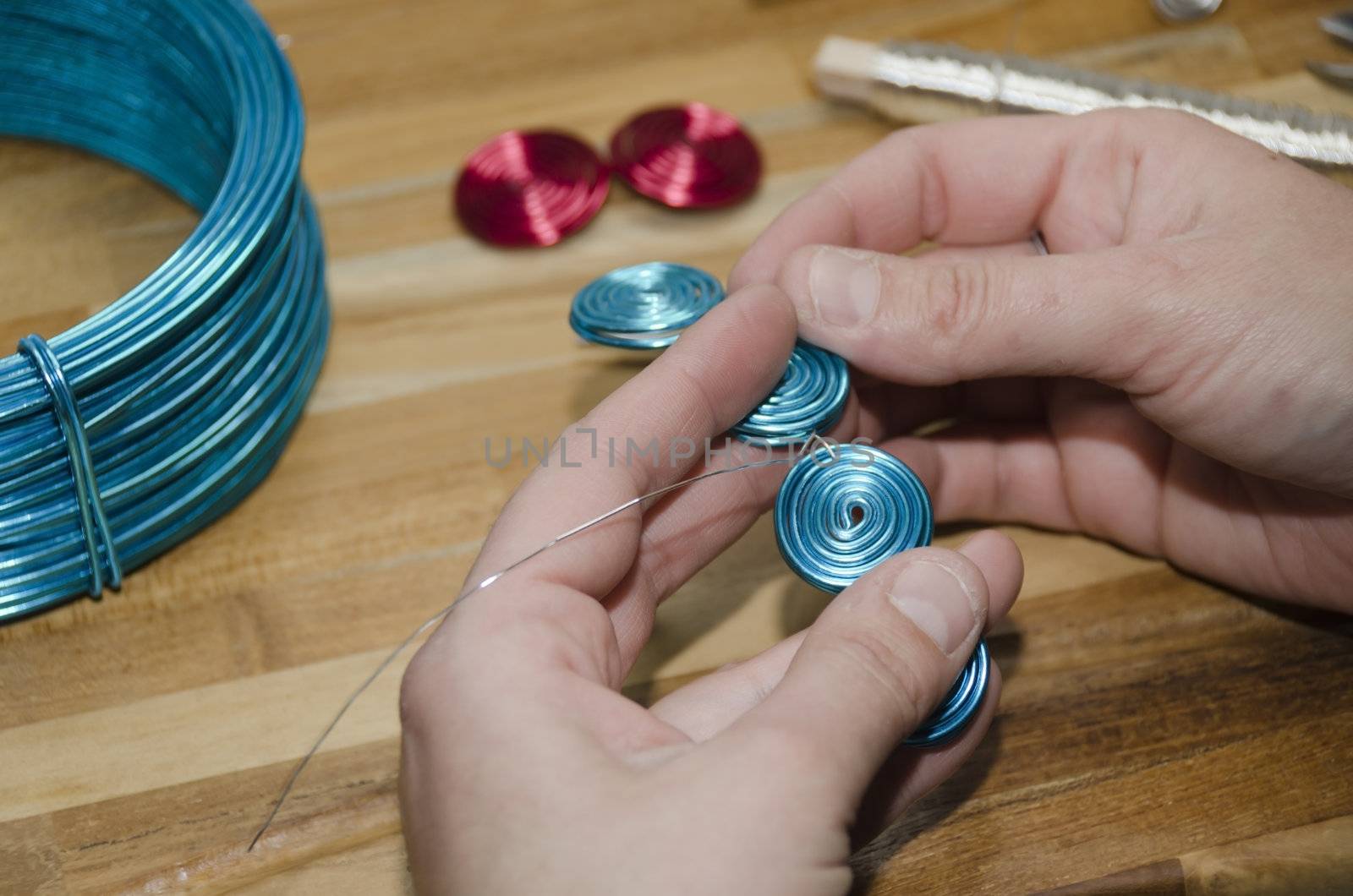woman's hand creating a fashion bracelet with blue metal